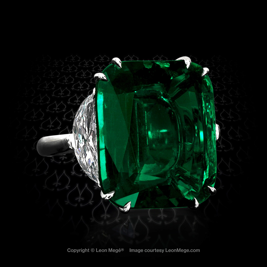 Classic three-stone ring featuring a cushion emerald by Leon Mege.