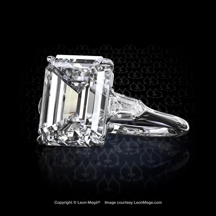 Classic three-stone ring featuring an emerald cut diamond with diamond bullets by Leon Mege.