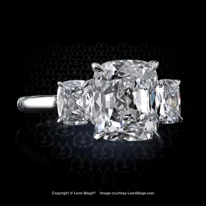Classic three-stone ring, featuring 4.02 carat Antique cushion diamond with cushion diamond side stones set in platinum by Leon Mege.