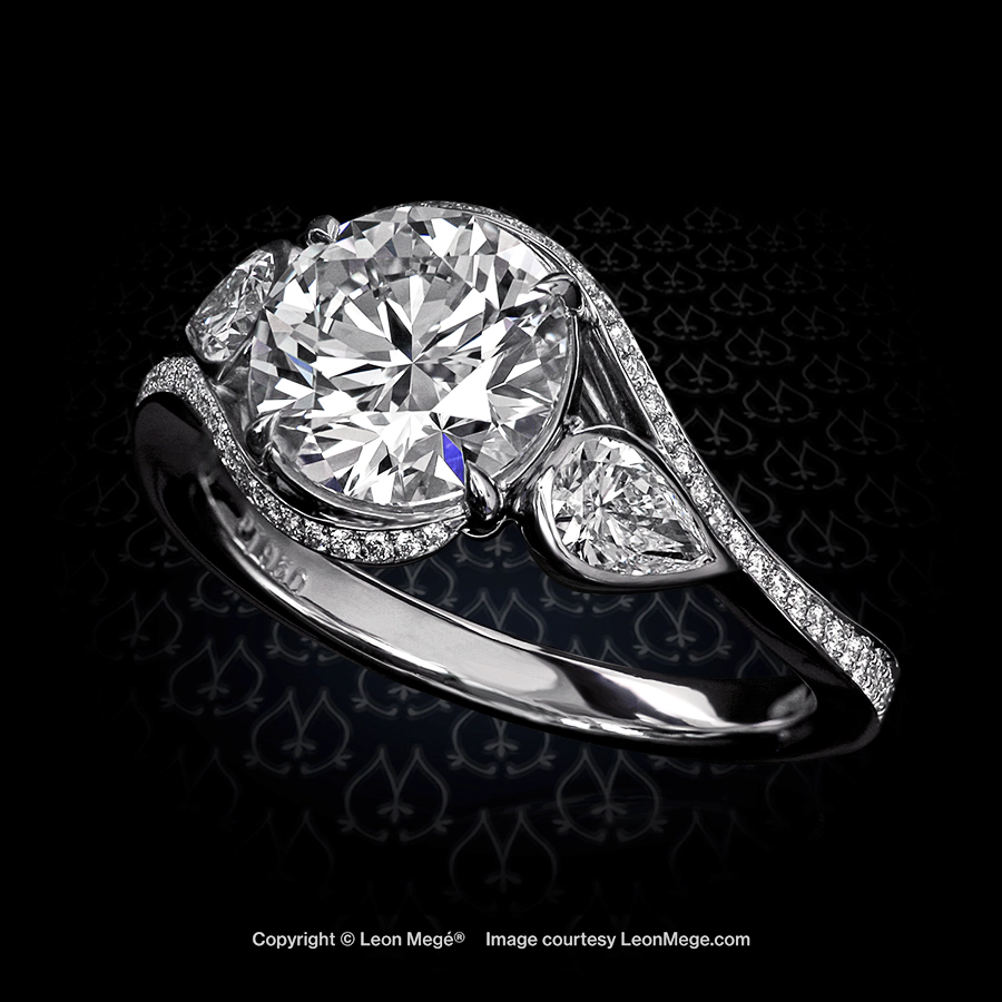 Freestyle three-stone ring, featuring 1.71-carat round diamond with bezel-set pear shapes on the sides and wraparound shank with bright-cut pave.